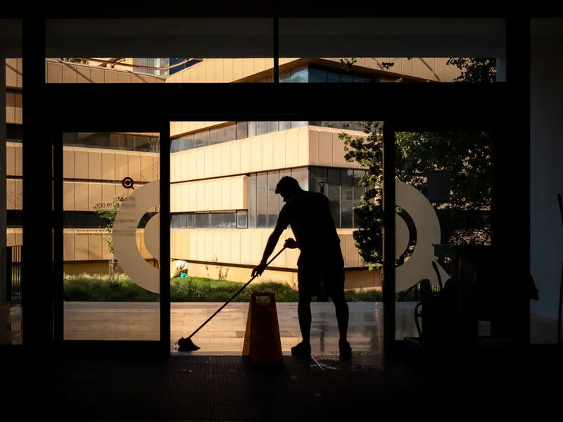Janitorial technician cleaning the entrance of a commercial building